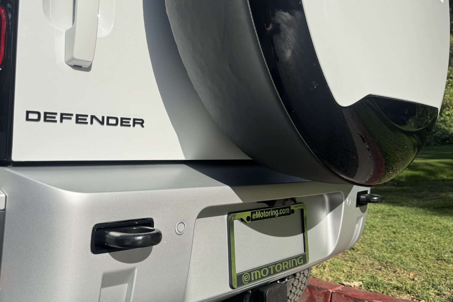 A white Land Rover Defender with an eMotoring plate frame