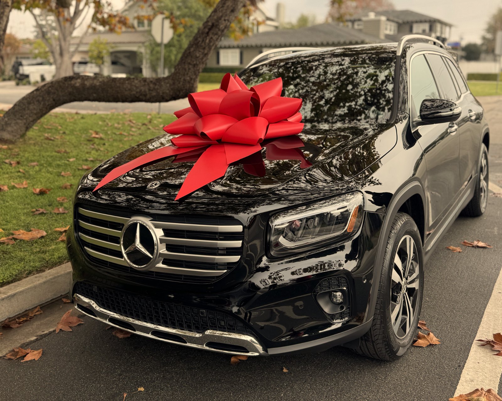 A black Mercedes-Benz GLB delivered with a red bow and eMotoring plate
